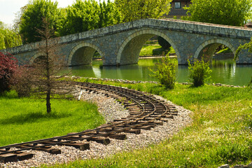 Vintage tourist railroad and old bridge upon small river in beautiful  ethnic village in Bosnia and Herzegovina