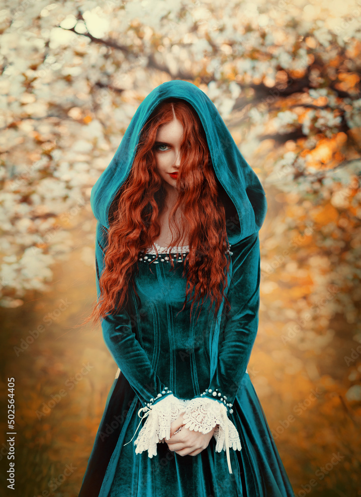Portrait mystical fantasy red-haired woman witch looking at camera. Girl  princess. Blue green medieval Victorian dress. Glamorous lady queen, red  long curly hair waving flying in wind. Autumn forest. Stock Photo |