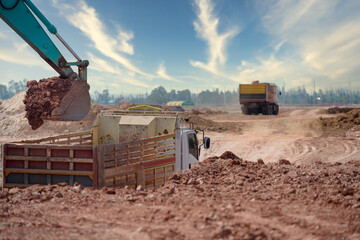 Close-up photo of excavator at a construction site A crawler excavator is shoveling soil into a large dump truck or trailer. The backhoe works by digging the soil at the construction site.