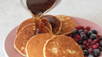 Wall Mural - Slow motion syrup pouring on pancakes served with berries. Sweet breakfast food