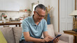 © PRPicturesProduction - portrait of asian Japanese retired man using mobile phone to read online news alone in the living room at home