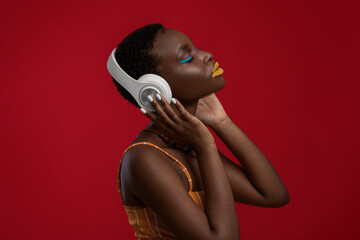 Delighted african american lady using wireless headset on red