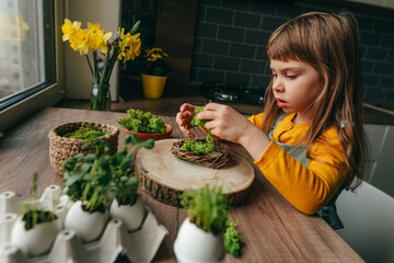 Wall Mural - Little girl decorating nest with green moss on the table