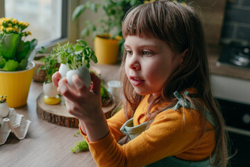 Wall Mural - Little girl decorating eggshell with toy eyes on the table