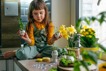 Wall Mural - Little girl decorating eggshell with toy eyes on the table