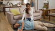 © PR Image Factory - Asian adult granddaughter hurrying over to her fallen grandpa in coma on floor and calling 911 on her mobile phone at home. elder senior fall and faint risk at home concept