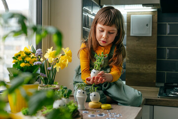 Wall Mural - Little girl decorating eggshell with toy eyes on the table