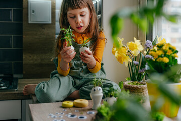 Wall Mural - Little girl decorating eggshell with toy eyes on the table