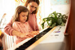 © JustLife - Woman and girl playing a piano. Beautiful woman teaching a little girl playing a piano.