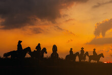 Group Cowboy On Horse Silhouetted Against A Large Sky