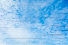 Beautiful Bright, Vivid And Colorful Horizontal Background Or Backdrop Of Blue Sky And White Clouds With Silhouetеes Of Wires Of Electrical Main Or Transmission Line In Sunny Day