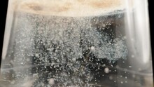 White powder dissolves in water, particles fall down, macro