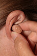 © SuperStock - Close-up of a woman's finger inserting a hearing aid in her ear