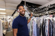 © SuperStock - Young African American small business owner talking with customer while pulling clothes off rack at dry cleaners