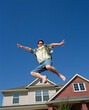 © SuperStock - Middle aged man jumping in front of home, striking a pose mid air