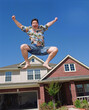 © SuperStock - Middle aged man jumping in front of home, striking a pose mid air