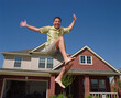 © SuperStock - Middle aged man jumping in front of home, striking a pose mid air
