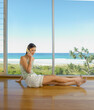© SuperStock - Young woman sitting on the floor and talking on mobile phone at beach house