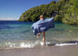 © SuperStock - Young woman wearing towel jumping over small waves at lake edge