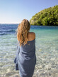 © SuperStock - Young woman standing wrapped in a towel by the lake edge