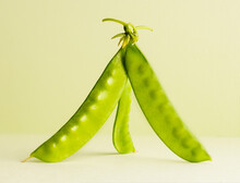 Three Green Snowpeas Standing Up On A Light Green Background