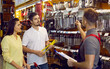 © Studio Romantic - Family in hardware store. Seller advises couple of customers on type of spanners in building materials store. Husband and wife buy tools for repairs, listen carefully to employee of store in overalls.