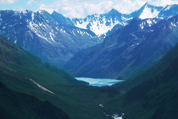 Wall Mural - In a high mountain gorge in Altai, among the snow-capped peaks, there is a blue lake, the slopes of the mountains are covered with forest, summer, sunny, the sky with clouds