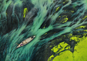 Villagers boating through green water plants in Bangladeshi rivers