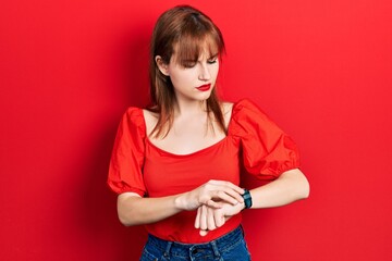 Poster - Redhead young woman wearing casual red t shirt checking the time on wrist watch, relaxed and confident