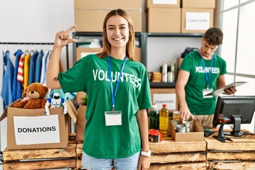 Poster - Young blonde girl wearing volunteer t shirt at donation stand smiling and confident gesturing with hand doing small size sign with fingers looking and the camera. measure concept.