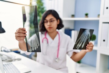 Canvas Print - Young latin woman wearing doctor uniform holding xray at clinic