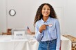 © Krakenimages.com - Young latin woman smiling confident pointing with finger to i voted badge at electoral college