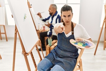 Canvas Print - Young artist woman at art studio pointing with finger to the camera and to you, confident gesture looking serious