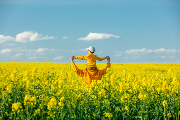 Father with a son in rapeseed field in spring time