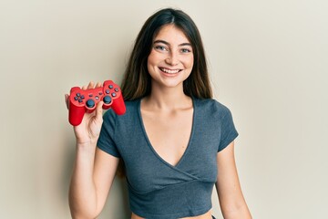 Sticker - Young caucasian woman playing video game holding controller looking positive and happy standing and smiling with a confident smile showing teeth