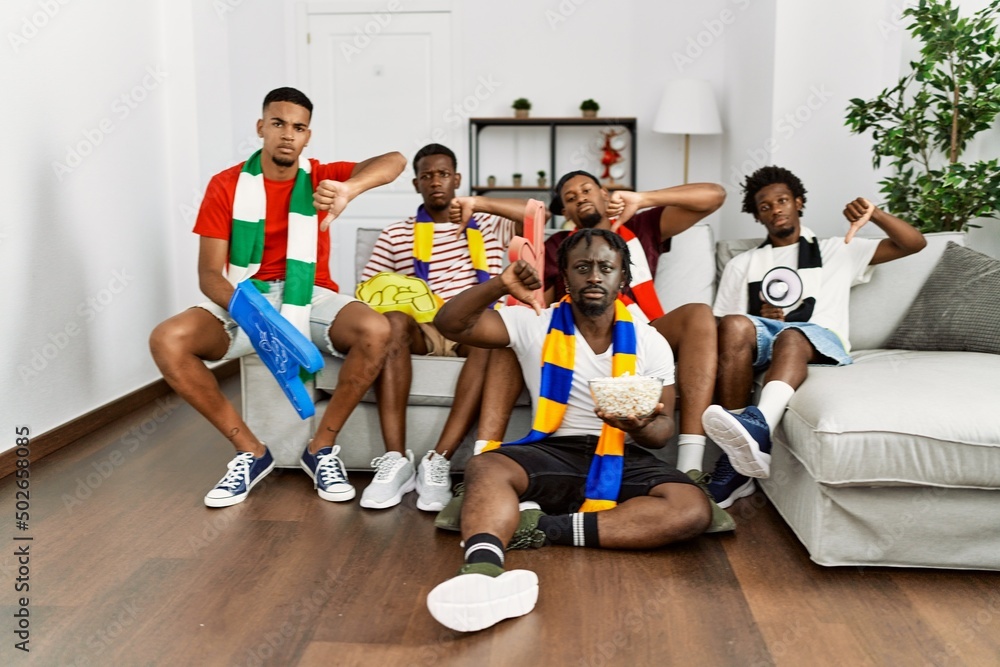 Young african men wearing team scarf cheering football game with angry ...