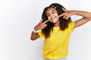 Poster - Young african american girl standing over white isolated background smiling cheerful showing and pointing with fingers teeth and mouth. dental health concept.