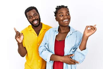 Poster - Young african american couple wearing casual clothes with a big smile on face, pointing with hand and finger to the side looking at the camera.