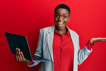 Sticker - Young african american woman holding laptop celebrating achievement with happy smile and winner expression with raised hand