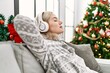 Young caucasian girl celebrating christmas listening to music sitting on the sofa at home.
