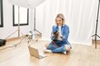 © Krakenimages.com - Beautiful blonde woman working as professional photographer at photography studio sitting on the floor checking photos on computer laptop