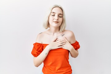 Sticker - Young caucasian woman standing over isolated background smiling with hands on chest with closed eyes and grateful gesture on face. health concept.