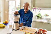 Senior Man Smiling Confident Shaking Blender At Kitchen