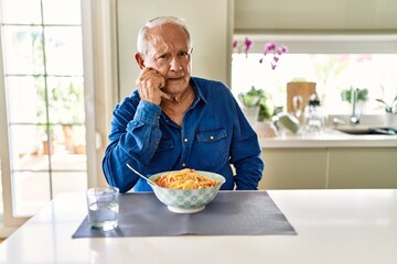 Poster - Senior man with grey hair eating pasta spaghetti at home looking stressed and nervous with hands on mouth biting nails. anxiety problem.