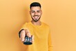 © Krakenimages.com - Young hispanic man with beard holding television remote control smiling with a happy and cool smile on face. showing teeth.