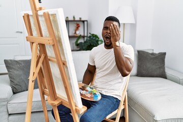 Canvas Print - Young african man painting on canvas at home yawning tired covering half face, eye and mouth with hand. face hurts in pain.