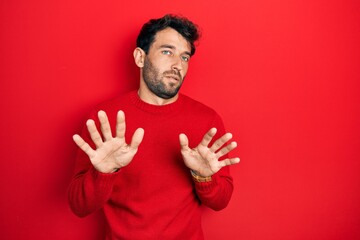 Poster - Handsome man with beard wearing casual red sweater moving away hands palms showing refusal and denial with afraid and disgusting expression. stop and forbidden.