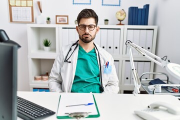 Sticker - Young man with beard wearing doctor uniform and stethoscope at the clinic depressed and worry for distress, crying angry and afraid. sad expression.