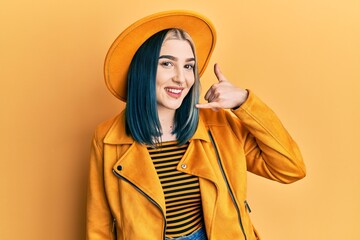 Sticker - Young modern girl wearing yellow hat and leather jacket smiling doing phone gesture with hand and fingers like talking on the telephone. communicating concepts.