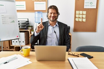 Sticker - Handsome middle age man wearing call center agent headset at the office showing and pointing up with finger number one while smiling confident and happy.